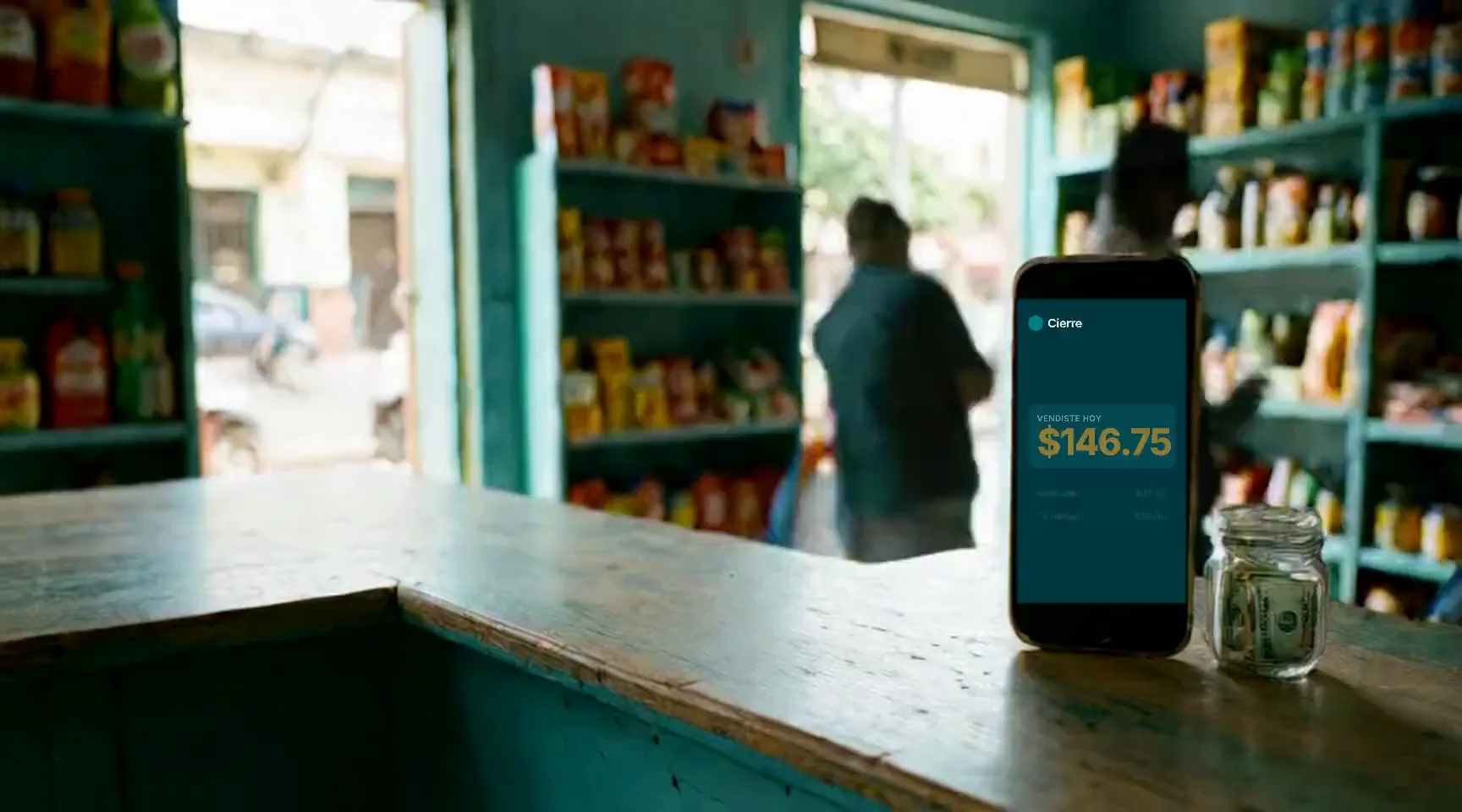 El mostrador de una tienda salvadoreña: el teléfono de pie con biyu abierto y un frasco con billetes.