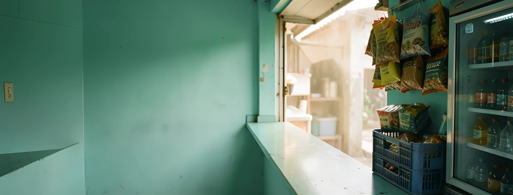 El mostrador de una tienda salvadoreña de día, con su pared verde azulado y la mercadería a la derecha